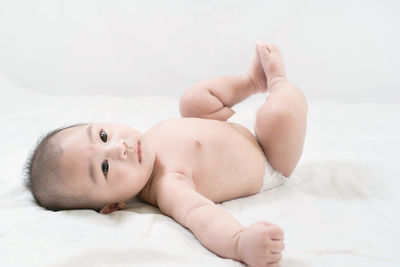 Portrait of a cute little baby boy in diaper lying on white bed.the care for the baby.