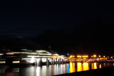 Blurred motion of illuminated bridge over river at night