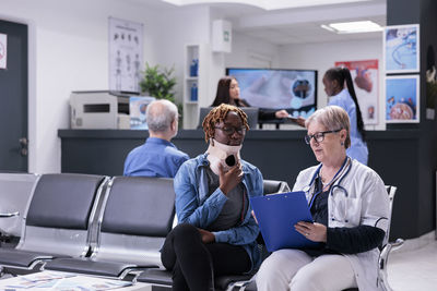 Female friends using phone while sitting in meeting