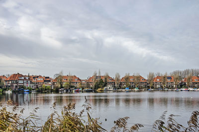 Buildings by river against sky in town