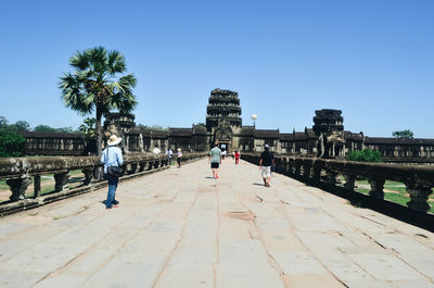 People walking in front of buildings against blue sky