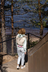 Rear view of woman standing by railing