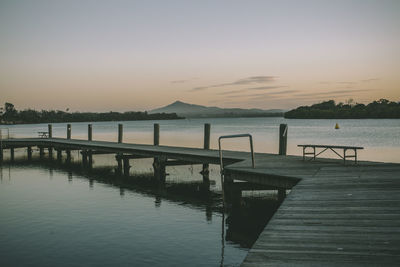 Pier on lake against sky during sunset