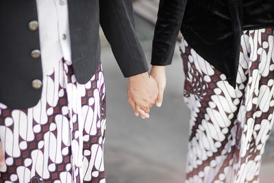 Midsection of couple holding hands