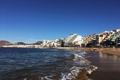 Buildings at waterfront against blue sky