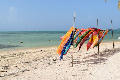 Multi colored fabric drying at beach against sky