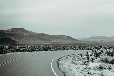 Road leading towards mountains against sky