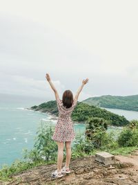 Rear view of woman standing by sea against sky