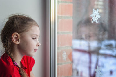 Portrait of girl looking through window