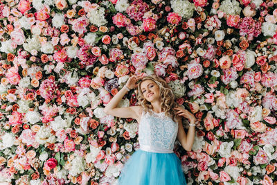 Young woman wearing blue dress standing against flowering plants