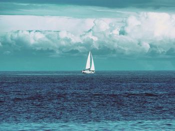 Sailboat sailing on sea against sky