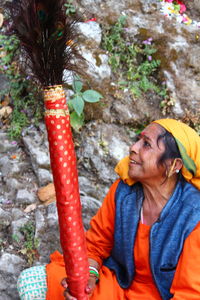 Woman holding peacock feathers while sitting outdoors