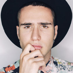 Close-up portrait of young man wearing hat against white background