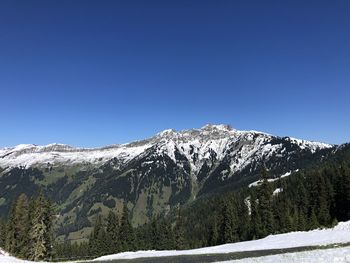 Scenic view of snowcapped mountains against clear blue sky