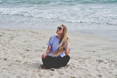 Young woman sitting on shore at beach