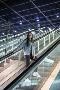 Full length of woman standing on escalator