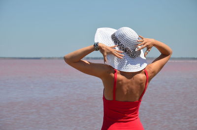 Midsection of woman standing by sea against sky