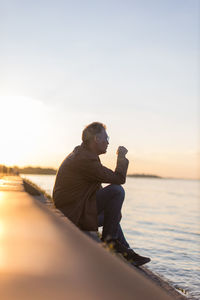 Lonely man sitting on the river bank