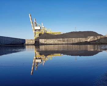 Crane by water against clear blue sky