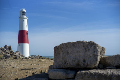 Lighthouse on rock by sea against sky