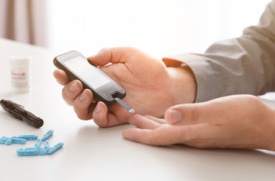 Midsection of man holding smart phone on table