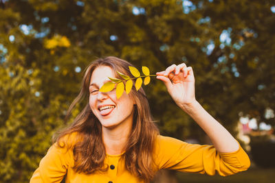 Woman sticking out tongue while holding leaves