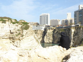 Buildings and rocks in city against sky