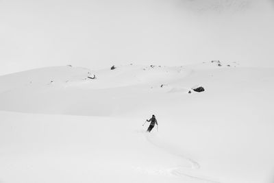 People skiing on snowcapped mountain against clear sky