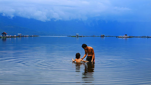 Grandfather and grandson swimming in lake