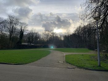 Empty road amidst field against sky