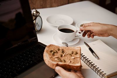 Midsection of man holding coffee cup on table