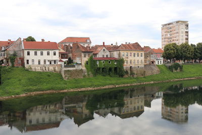 Reflection of houses and buildings in lake against sky