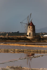 Traditional windmill by lake against sky