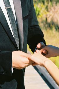 Midsection of couple holding hands while standing outdoors