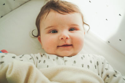 Directly above shot of cute baby girl lying on bed at home