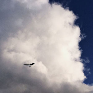 Low angle view of airplane flying against cloudy sky