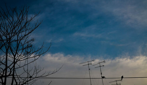 Low angle view of bare tree against cloudy sky