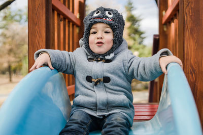 Portrait of cute baby boy sitting on slide at playground