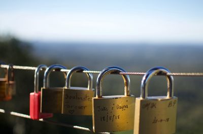 Close-up of padlocks on railing against sky