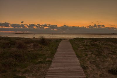 Footpath leading towards sea during sunset