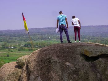 Rear view of men standing on field against clear sky