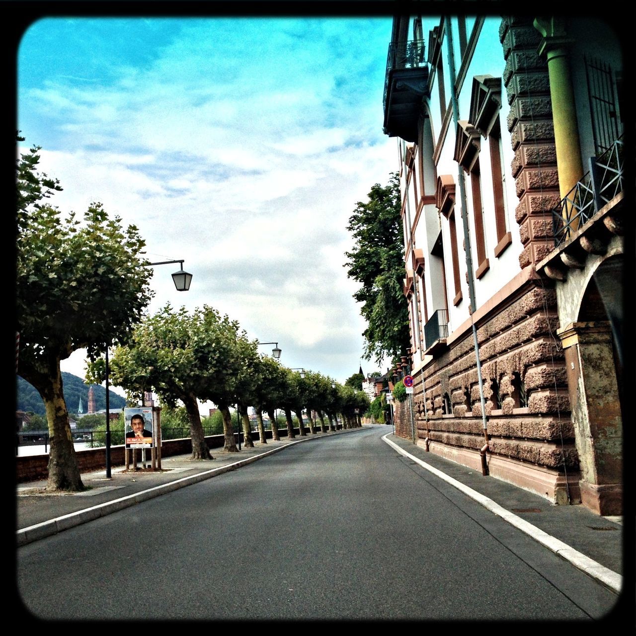 architecture, building exterior, built structure, the way forward, street, sky, transfer print, diminishing perspective, road, city, tree, transportation, auto post production filter, road marking, building, car, cloud - sky, vanishing point, incidental people, cloud