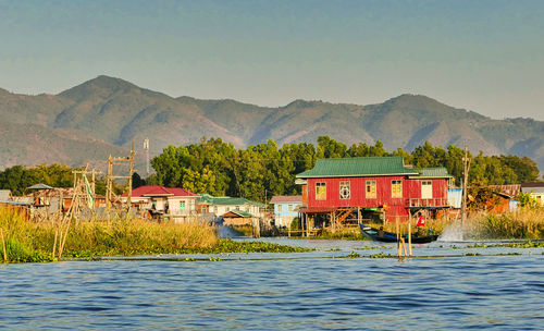 House by lake and mountains against sky