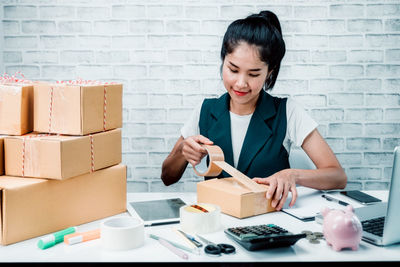 Smiling young woman holding cigarette in box on table