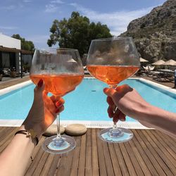 Woman holding ice cream by swimming pool against sky