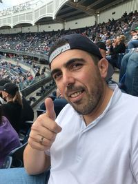 Portrait of smiling man showing thumbs up at stadium