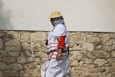 Side view of man standing against stone wall