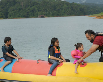 Father with kids standing by boat in lake