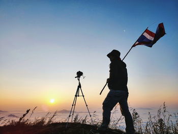 Man photographing on field against clear sky during sunset