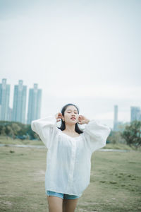 Full length of young woman standing against sky